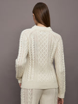 Model wearing a cream colored vertically textured wide cable knit sweater. 