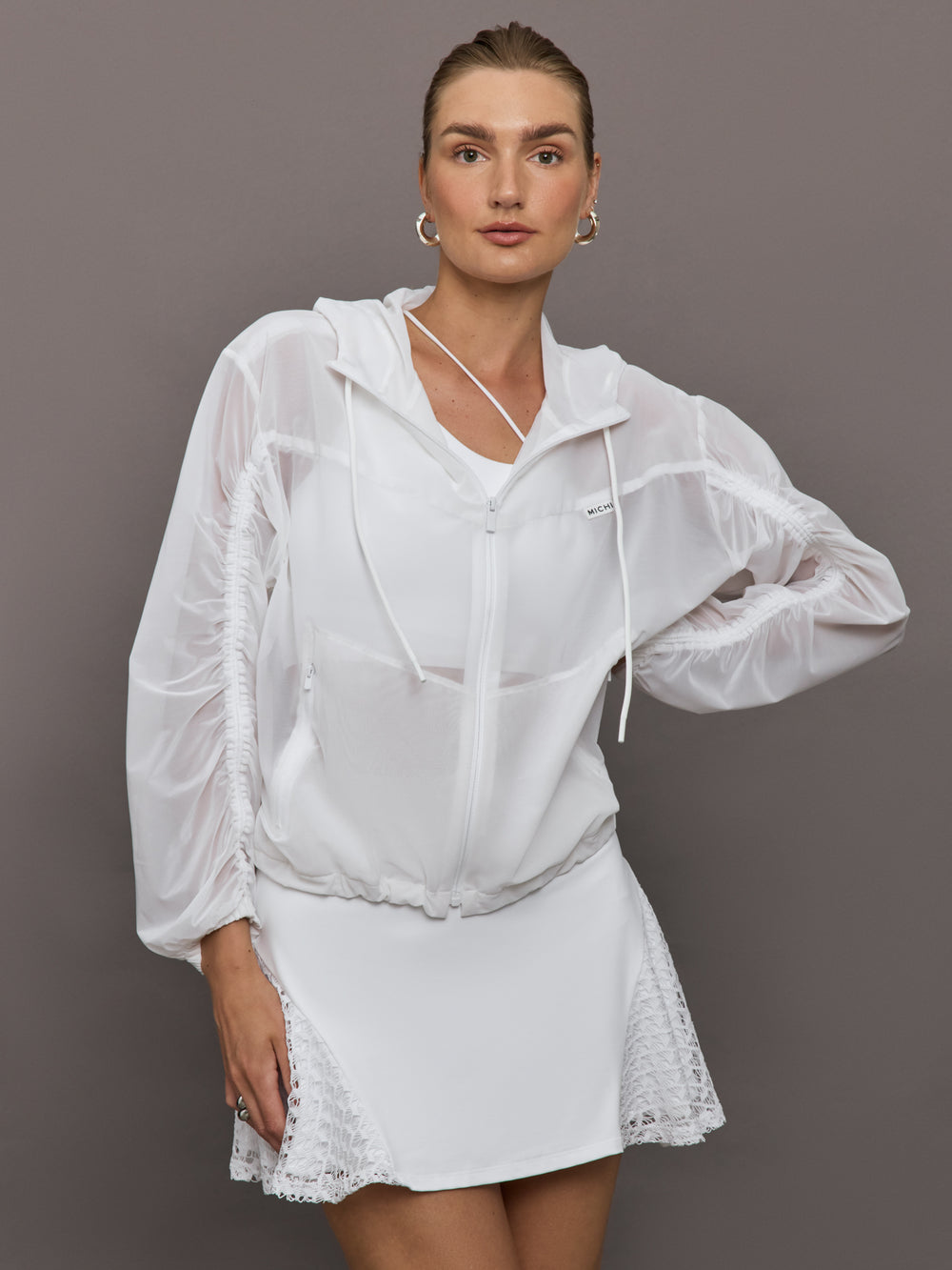 Model wears white Indy Jacket with a relaxed fit and full zip front, with elastic cuffs and a sheer, lightweight fabric for a translucent look.