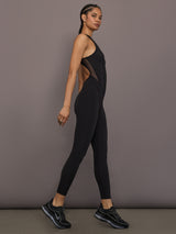 Model is wearing the Odyssey Jumpsuit in black, side view while walking.