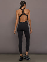 Model is wearing the Odyssey Jumpsuit in black, back full body view.