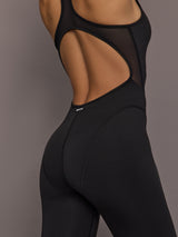 Model is wearing the Odyssey Jumpsuit in black, back cut out and mesh detail close up.