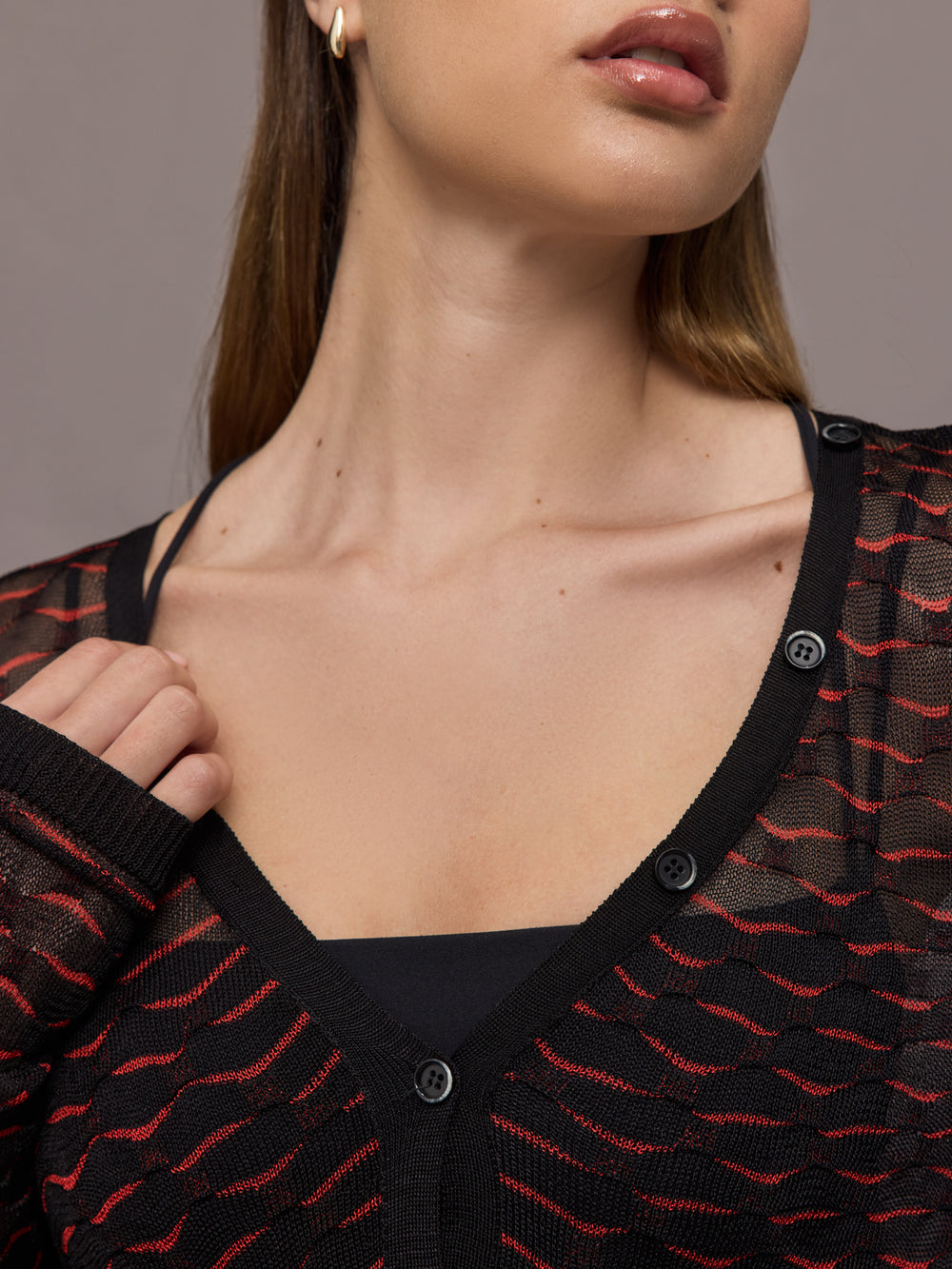 Woman wearing a black and red patterned long-sleeve top against a gray background