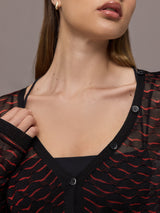 Woman wearing a black and red patterned long-sleeve top against a gray background