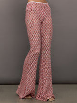 Model wears mid-waisted red flare trousers with an abstract patterned design throughout.
