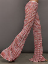 Model wears mid-waisted red flare trousers with an abstract patterned design throughout.