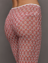 Model wears mid-waisted red flare trousers with an abstract patterned design throughout.