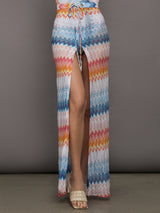 Model wears a high waisted drawstring floor length skirt with an A-line hem up the center and patterned multicolor chevron.