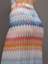 Model wears a high waisted drawstring floor length skirt with an A-line hem up the center and patterned multicolor chevron.