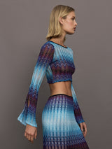 Model wears a multi-blue long-sleeve cropped top with a form-fitting silhouette.