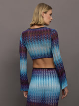 Model wears a multi-blue long-sleeve cropped top with a form-fitting silhouette.