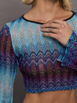 Model wears a multi-blue long-sleeve cropped top with a form-fitting silhouette.
