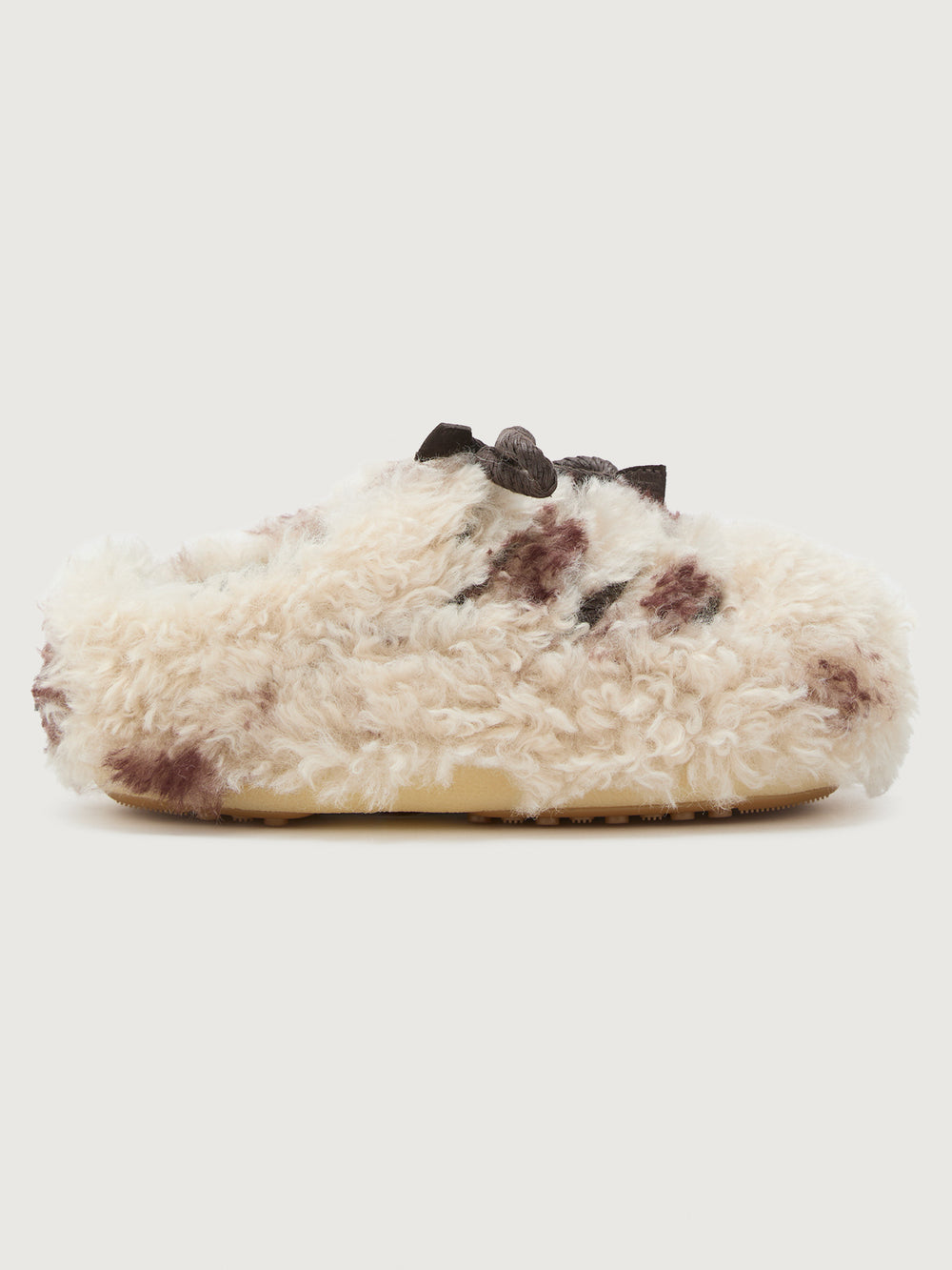 White fuzzy slipper with brown speckles on a light gray background
