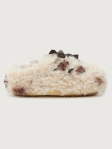 White fuzzy slipper with brown speckles on a light gray background