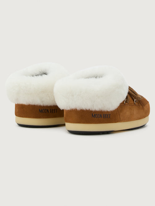 Pair of brown suede slippers with white fur lining on a light gray background