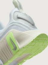 White athletic shoe with neon green sole.