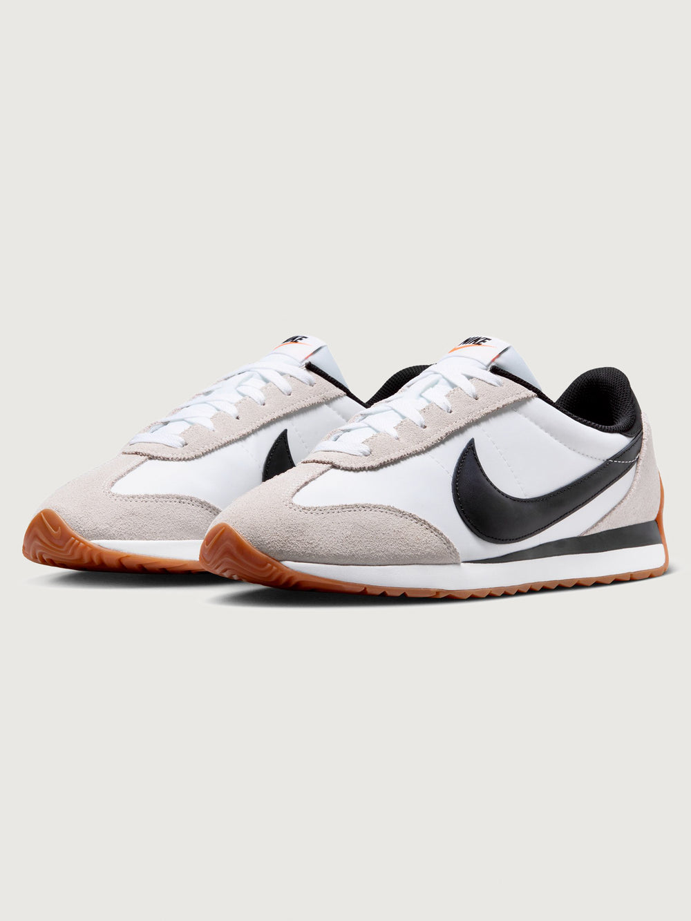 White and black sneaker with a brown sole on a light gray background