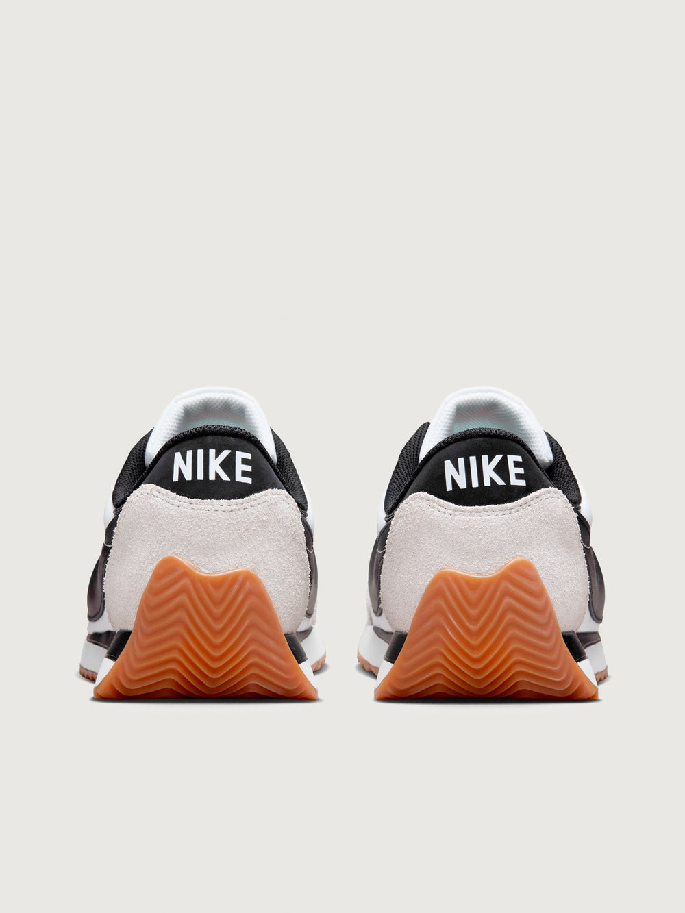 White and black sneaker with a brown sole on a light gray background
