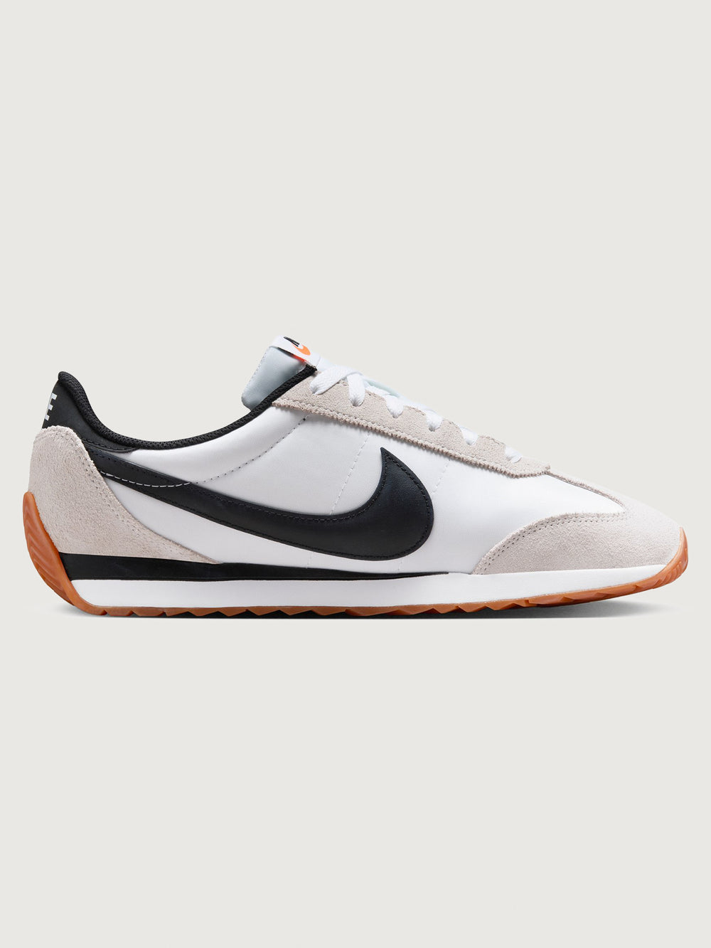 White and black sneaker with a brown sole on a light gray background