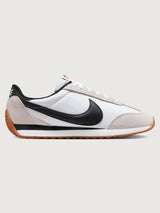 White and black sneaker with a brown sole on a light gray background