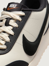 Women’s Pacific Leather trainer in Sail and Off Noir, Swoosh logo close-up.