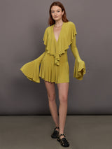 Model wears long sleeve mini dress in asparagus green with a deep V-neckline and ruffle detailing.
