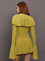 Model wears long sleeve mini dress in asparagus green with a deep V-neckline and ruffle detailing.
