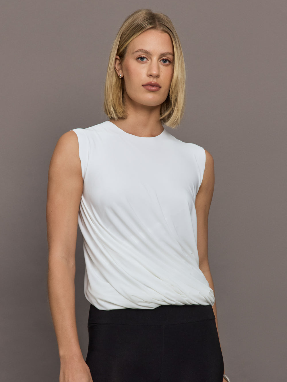 Model is wearing Sleeveless Twist Top in Snow White, front view.