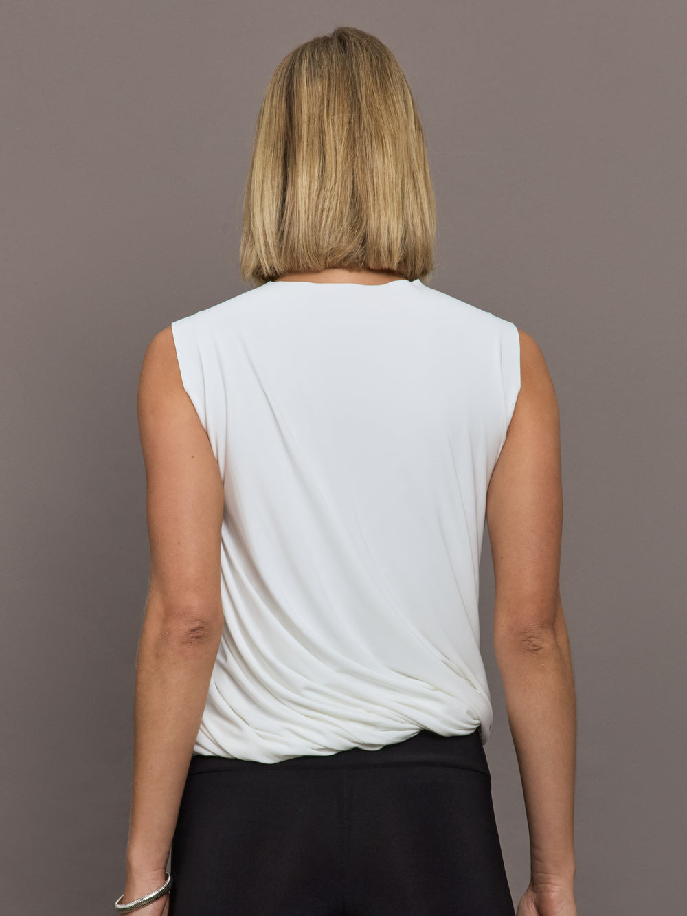 Model is wearing Sleeveless Twist Top in Snow White, back view.