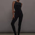 Model wears a black sleeveless X catsuit with built-in footies, featuring a high neckline, body-contouring fit, and crisscross X straps on the back