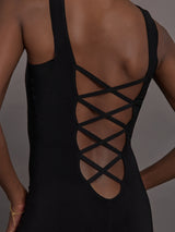 Model wears a black sleeveless X catsuit with built-in footies, featuring a high neckline, body-contouring fit, and crisscross X straps on the back