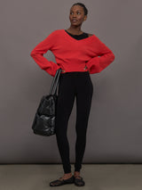 Model wears a black sleeveless X catsuit with built-in footies, featuring a high neckline, body-contouring fit, and crisscross X straps on the back