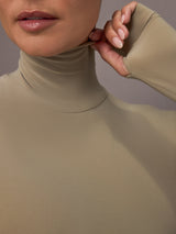 Model wearing a beige long-sleeve bodysuit.