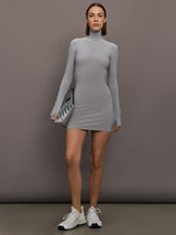 Model is wearing Long Sleeve Turtleneck Mini Dress in Grey, full body view styled with sneakers and clutch.