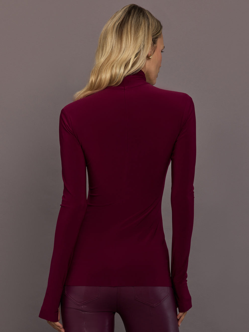 Model is wearing Slim Fit Long Sleeve Turtle Top in Plum, back view with center back seam.