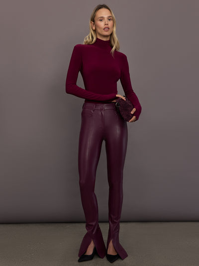 Model is wearing Slim Fit Long Sleeve Turtle Top in Plum, full body front view styled with vegan leather pants.