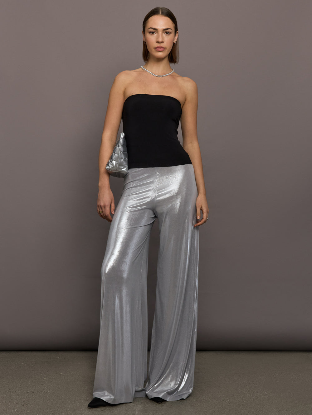 Model is wearing Strapless Contour Top in Black, full body view styled with silver wide-leg pants.