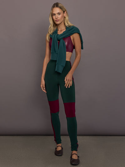 Model is wearing Side Stripe Legging With Knee Patch in Dark Emerald and Plum, full body front view styled with plum top and sweater.