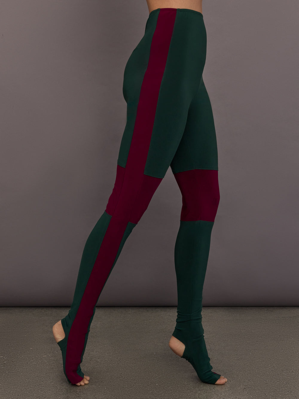 Model is wearing Side Stripe Legging With Knee Patch in Dark Emerald and Plum, side view with pointed toe and stripe detail.