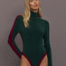 Model is wearing Side Stripe Zip Front Long Sleeve Turtleneck Bodysuit in Dark Emerald and Plum, front view.