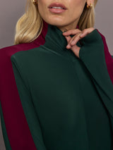 Model is wearing Side Stripe Zip Front Long Sleeve Turtleneck Bodysuit in Dark Emerald and Plum, close-up of zip front and collar.
