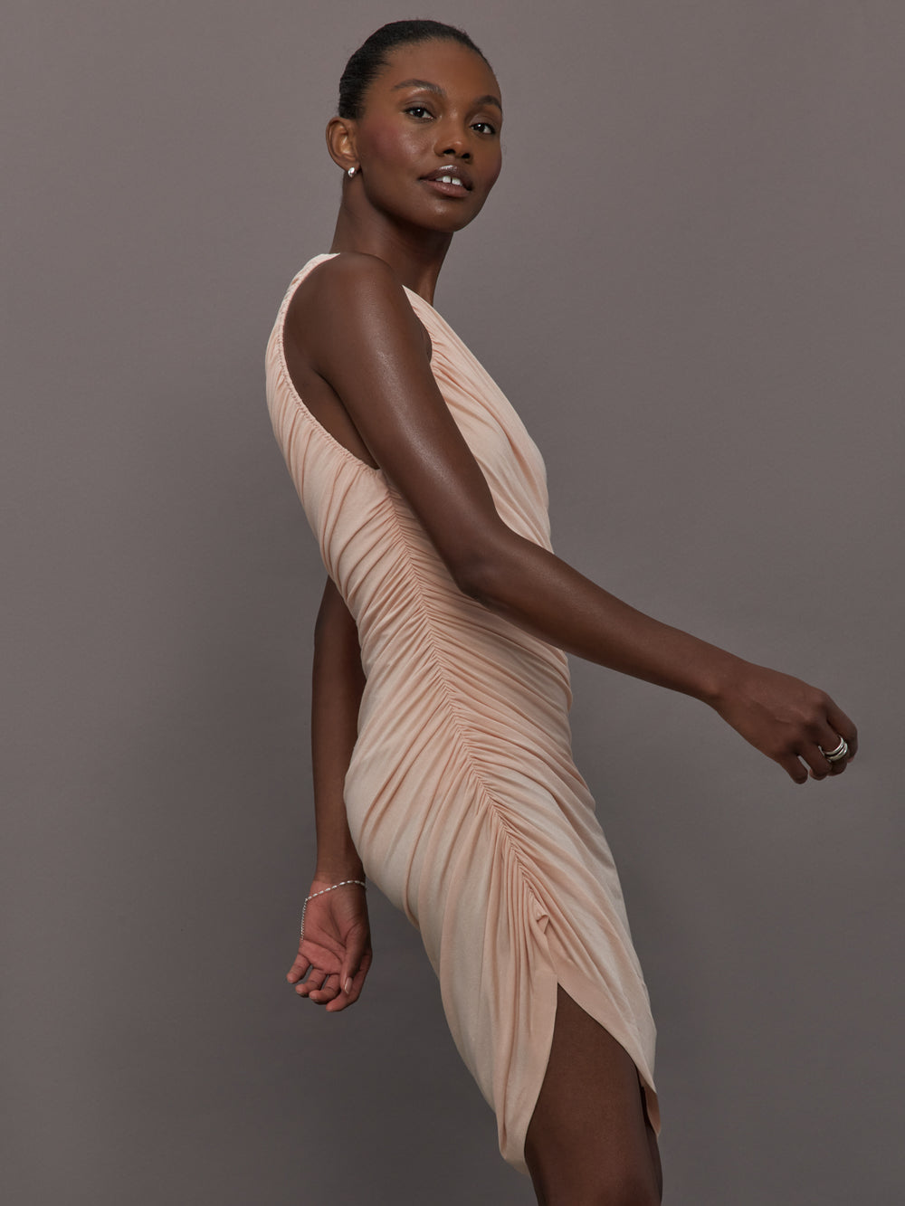 Model wears the Diana Mini Dress in Baby Pink, featuring a sleeveless, asymmetrical design with a fitted bodice