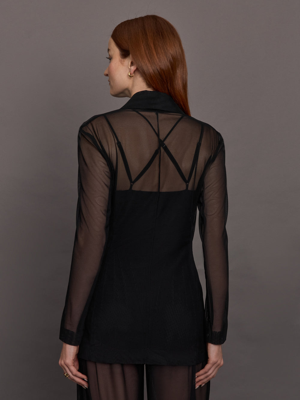 Model wears black single-breasted mesh jacket with a collared neck and tailored fit.
