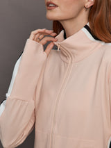Model wears baby pink jacket with a turtleneck, front zipper, and side stripes on the sleeves.
