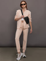 Model wears baby pink jacket with a turtleneck, front zipper, and side stripes on the sleeves.
