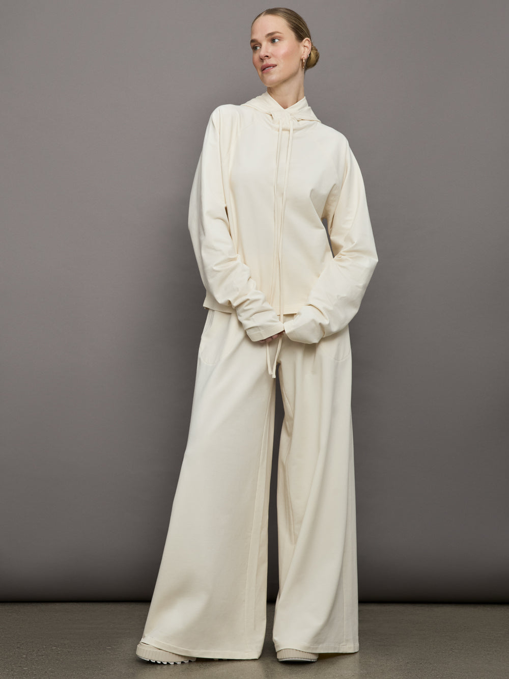 Model wears a pair of oversized wide leg cream colored sweatpants. 