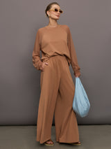 Model wears a pair of oversized, wide legged, light brown sweatpants.