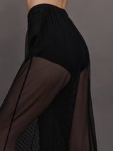 Model wears black high-waisted mesh pants with a wide leg fit.
