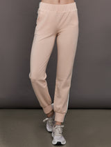 Model wears baby pink jogger pants with side stripes, elastic waistband, and cuffed ankles.




