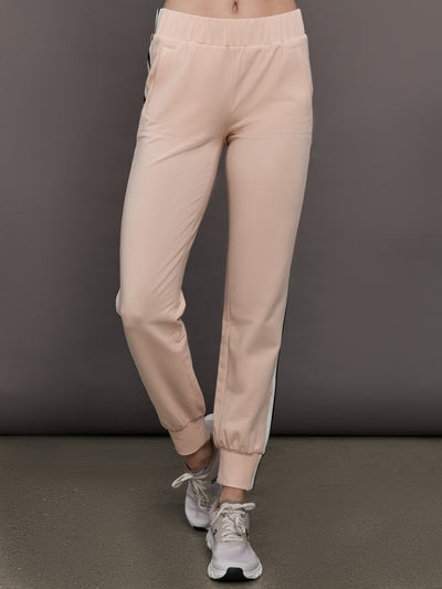Model wears baby pink jogger pants with side stripes, elastic waistband, and cuffed ankles.




