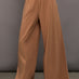 Model wears a pair of oversized, wide legged, light brown sweatpants.